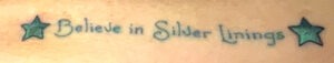 A tattoo with the words, "Believe in Silver Linings" with two stars.