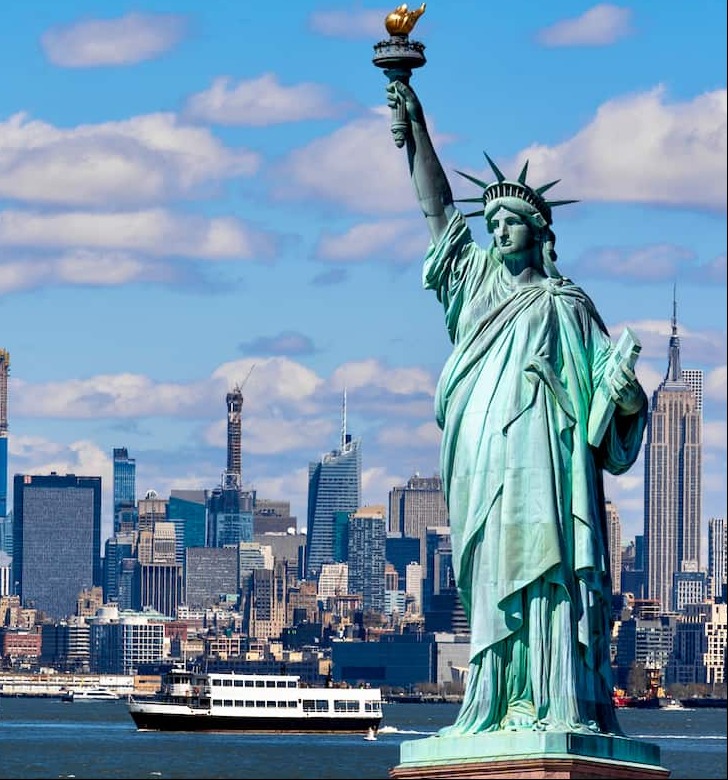 Statue of Liberty with ferry and New York City in the background.