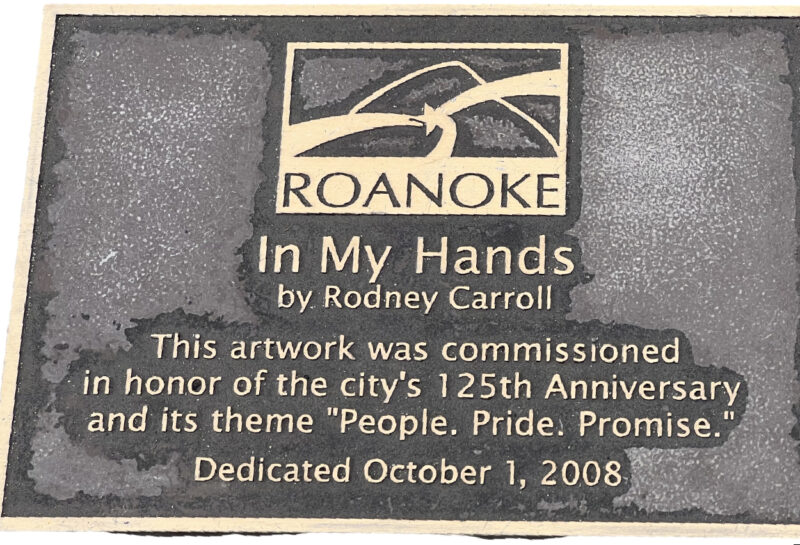 Brass plaque, which reads: ROANOKE/In My Hands/by Rodney Carroll/The artwork was commissioned/in honor of the city's 125th Anniversary/and its theme "People. Pride. Promise."/Dedicated October 1, 2008.