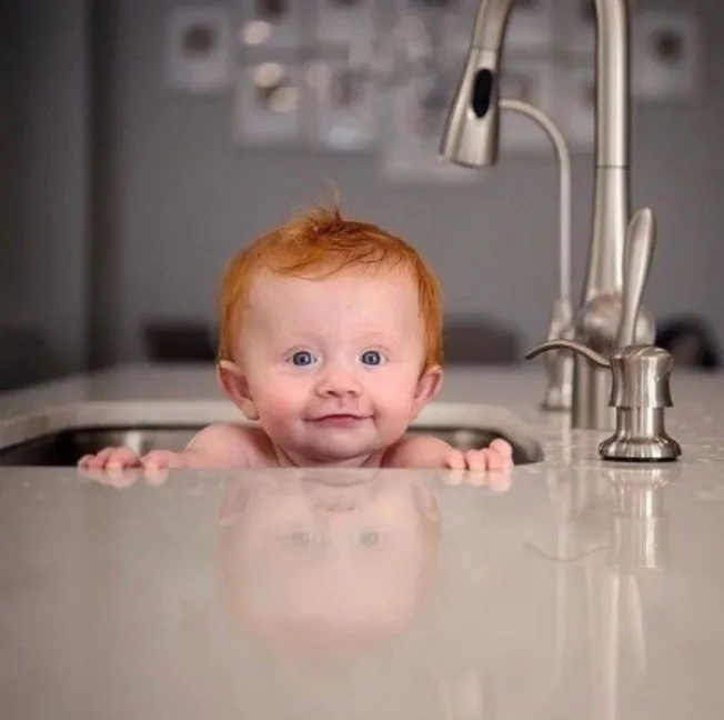 Poetic High Jinks: Red-headed toddler in a stainless steel, kitchen sink.