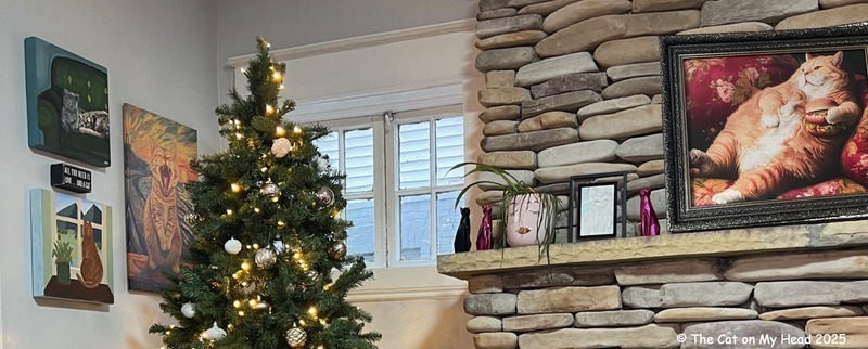 Periwinkle Stinky Toebean Cat Cafe The top of a Christmas Tree and fireplace with cat art on the wall and the mantle.