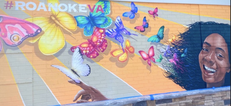 Periwinkle Stinky 300th Adventure Mural of an African American woman and colorful butterflies with the words, "#RoanokeVa," by Jon Murrill.