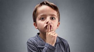 Young boy holding is finger to his lips and going, "shhh."