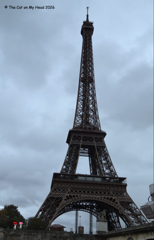 The Eiffel Tower with two tiny cartoon cats wearing berets. 
